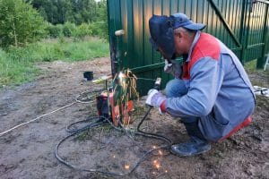 a professional fence installer welding a metal fence